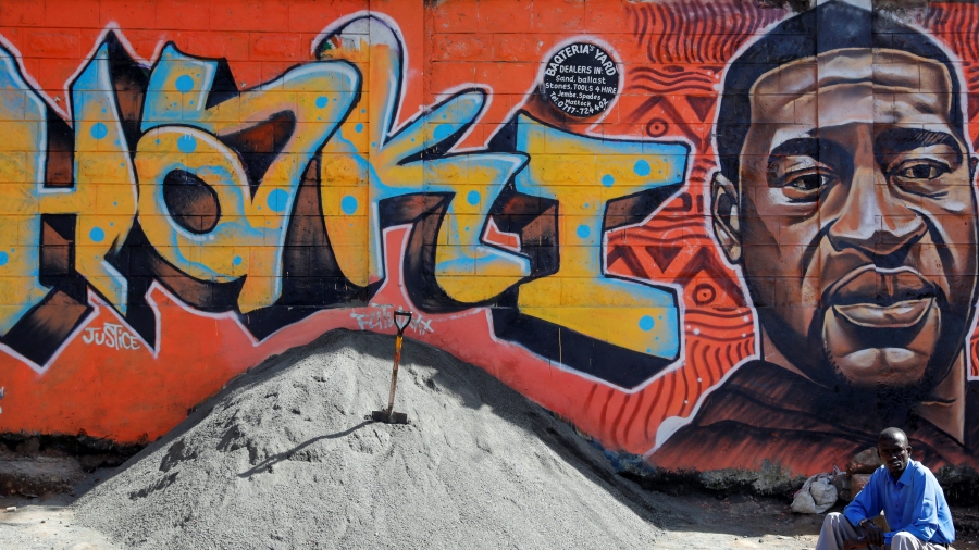 A man sits under a graffiti depicting African American man George Floyd, who was killed by a police officer in Minneapolis, in Kibera, Nairobi, Kenya, June 4, 2020. The writing reads ''Justice'' in Swahili. A man sits under a graffiti depicting African American man George Floyd, who was killed by a police officer in Minneapolis, in Kibera, Nairobi, Kenya.
