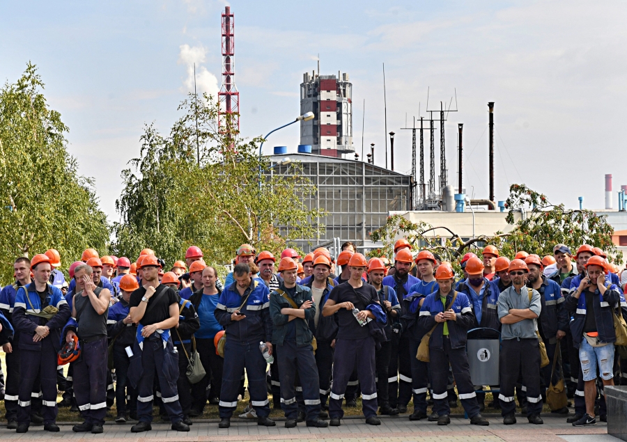 Workers at Grodno Azot, a Belarusian manufacturer, on strike. A large group of men with hard hats standing outside of their work's manufacturing facility.