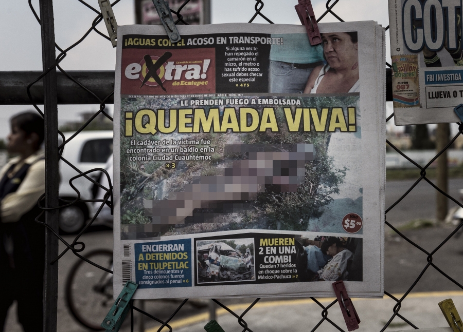 A Mexican newspaper exclaims ‘Burnt Alive!’ to tout a story about a murdered woman, June 7, 2015. The front page of a newspaper displayed on a fence.