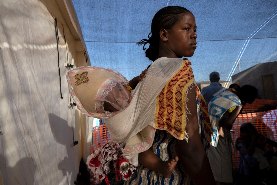 A Tigray refugee mother carries her child as she waits her turn for treatment at a clinic run by Doctors Without Borders in Village 8, the transit center near the Lugdi border crossing, eastern Sudan, Dec. 8, 2020.