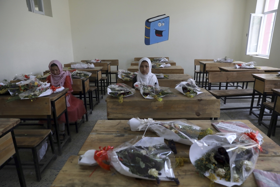 Schoolgirls sit inside a classroom with bouquets of flowers on empty desks as a tribute to the dozens killed in the May 8 bombing in Afghanistan Schoolgirls sit inside a classroom with bouquets of flowers on empty desks in Afghanistan