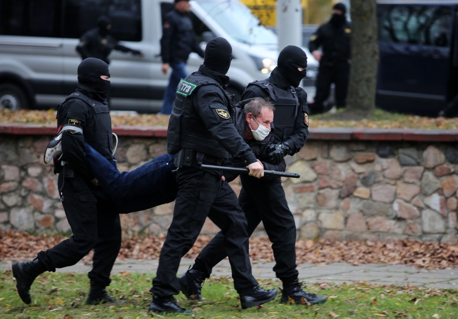Police arresting a protester at an anti-government march last year. Three police officers in uniform carry a man by his arms and legs.