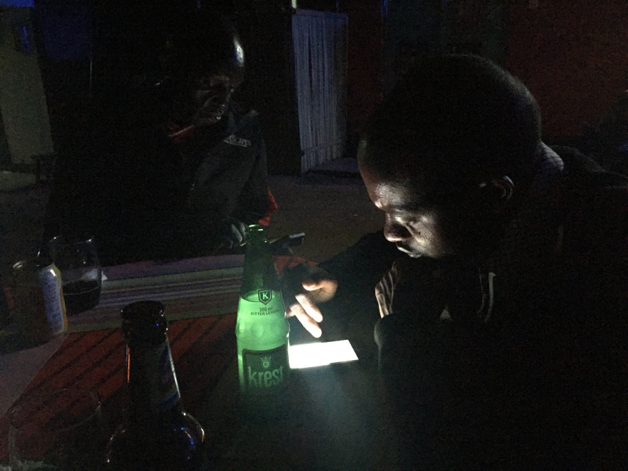 Two Maasai men check their phones at a local bar. Two Maasai men check their phones at a local bar.