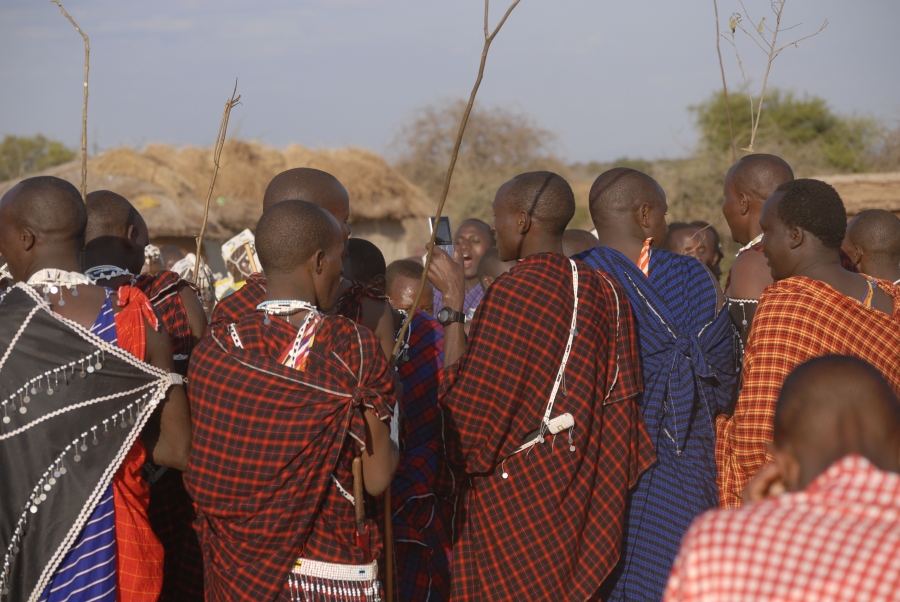 A young Maasai man checks his phone during a ceremonial dance. A young Maasai man checks his phone during a ceremonial dance.
