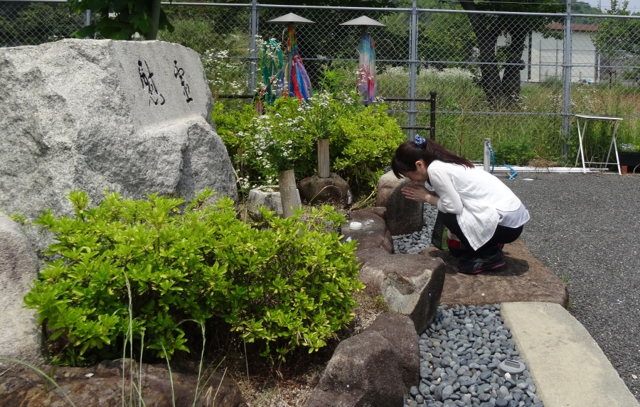 Aya Kano pays her respects at a shrine to the dead of Ninoshima. Aya Kano pays her respects at a shrine to the dead of Ninoshima.