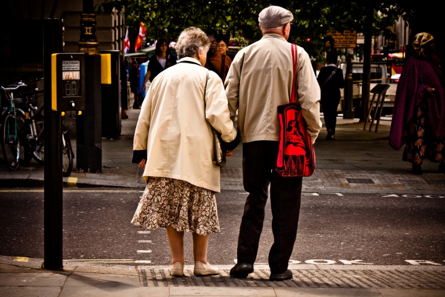 An elderly couple holds hands while waiting to cross a London street. An elderly couple holds hands while waiting to cross a London street.