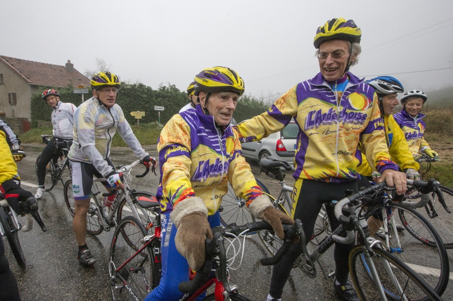 Robert Marchand (C), 103 years-old, speaks with riders as he makes his way along the Robert Marchand pass