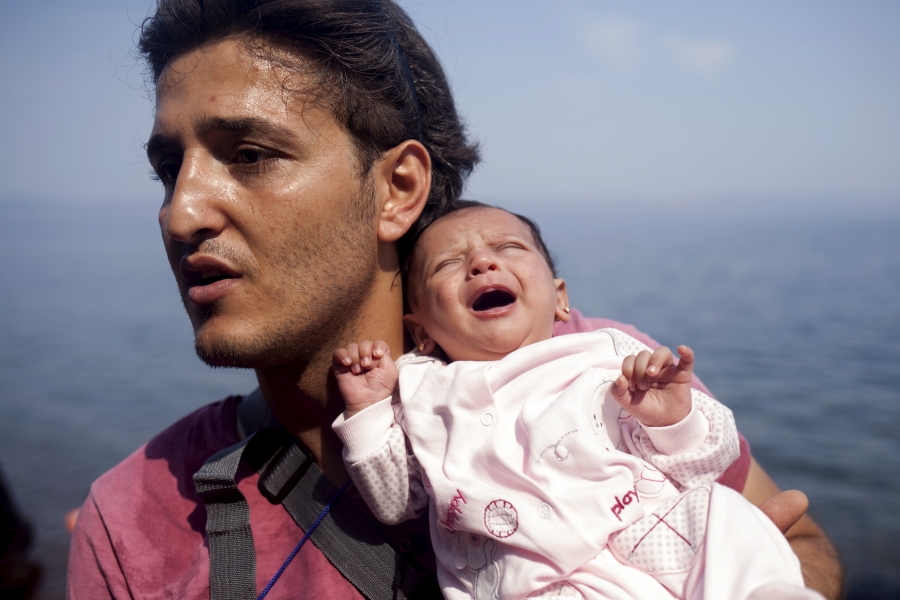 A Syrian refugee from Aleppo holds his one month old daughter moments after arriving on a dinghy on the Greek island of Lesbos A Syrian refugee from Aleppo holds his one month old daughter moments after arriving on a dinghy on the Greek island of Lesbos