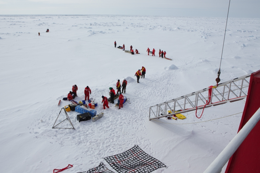 Team on ice Crew and scientists traveling on the U.S. Coast Guard icebreaker Healy unload equipment in the lee of the parked ship before hiking off to set up their research projects in undisturbed snow.