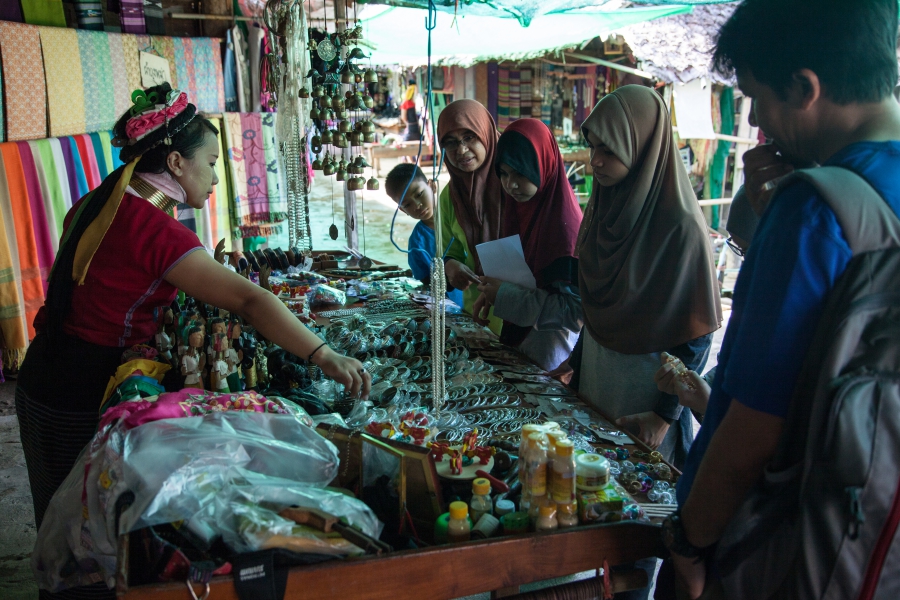 Tourists from Malaysia browse handicrafts at one of the many stalls lining the one main road through Huai Sua Tao.