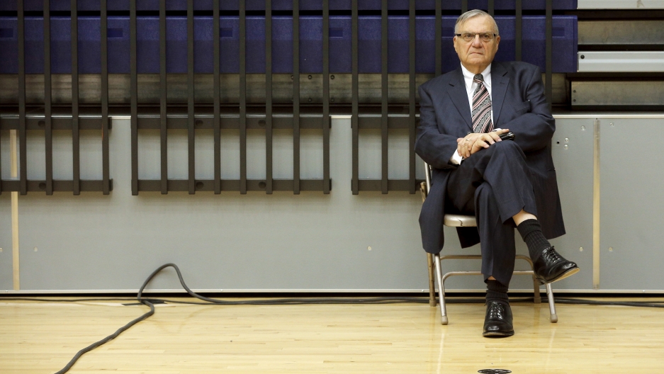 Arpaio sits on a folding chair in a gym