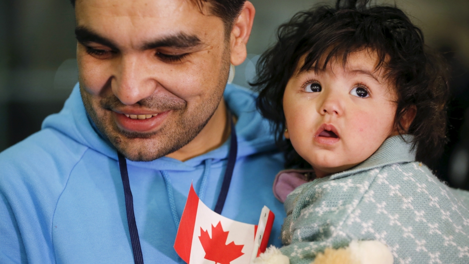 A Syrian refugee holds his daughter as they arrive at the Pearson Toronto International Airport in Mississauga, Ontario, December 18, 2015.