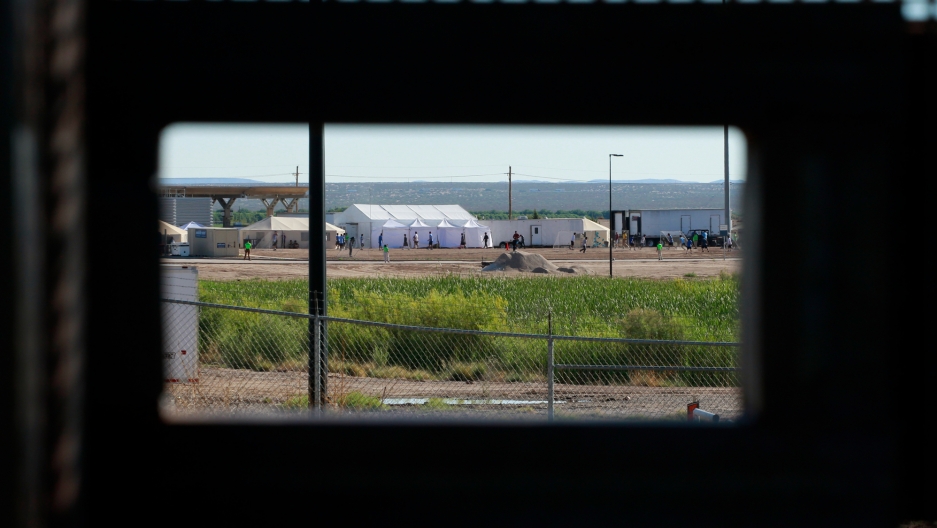 Children of detained migrants play soccer at a newly constructed tent encampment as seen through a border fence near the US Customs and Border Protection port of entry in Tornillo, Texas, June 18, 2018. In the distance children of detained migrants are seen play soccer at a tent encampment near the US Customs and Border Protection port of entry in Tornillo, Texas.