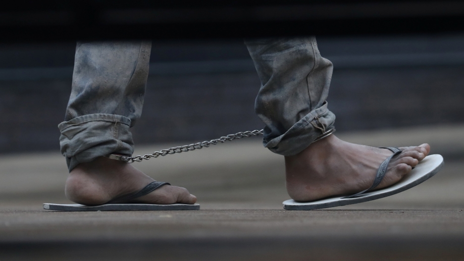 Undocumented immigrants in shackles arrive at a US federal court for hearings in McAllen, Texas, June 22, 2018. An undocumented immigrant is shown in shackles in a picture taken on the other side of a vehicle from underneath, just showing the feet.