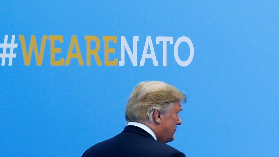 US President Donald Trump attends the welcoming ceremony at the start of a NATO summit in Brussels. US President Donald Trump walks past a blue wall with #wearenato printed on it.