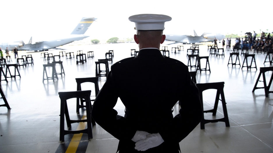 A US Marine stands at attention as caskets containing the remains of American servicemen from the Korean War handed over by North Korea arrive at Joint Base Pearl Harbor-Hickam in Honolulu, Hawaii, August 1, 2018. A US Marine is shown from behind standing at attention in full uniform as caskets containing the remains of American servicemen from the Korean War.