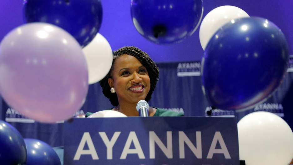 Balloons fall around Democratic candidate for the US House of Representatives Ayanna Pressley, at her primary election night rally in Boston, Massachusetts, September 4, 2018. Balloons fall around Democratic candidate for the US House of Representatives Ayanna Pressley as she stands behind a podium smiling.