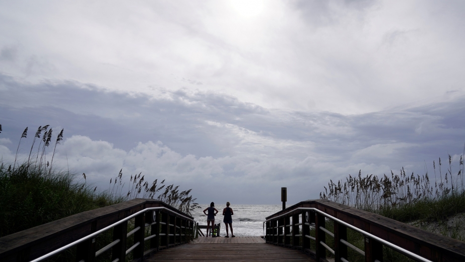People look out over the surf before Hurricane Florence comes ashore on Carolina Beach, North Carolina, Sept. 13, 2018. People look out over the surf at the end of a long wooden walkway with the ocean and large clouds off in the distance.