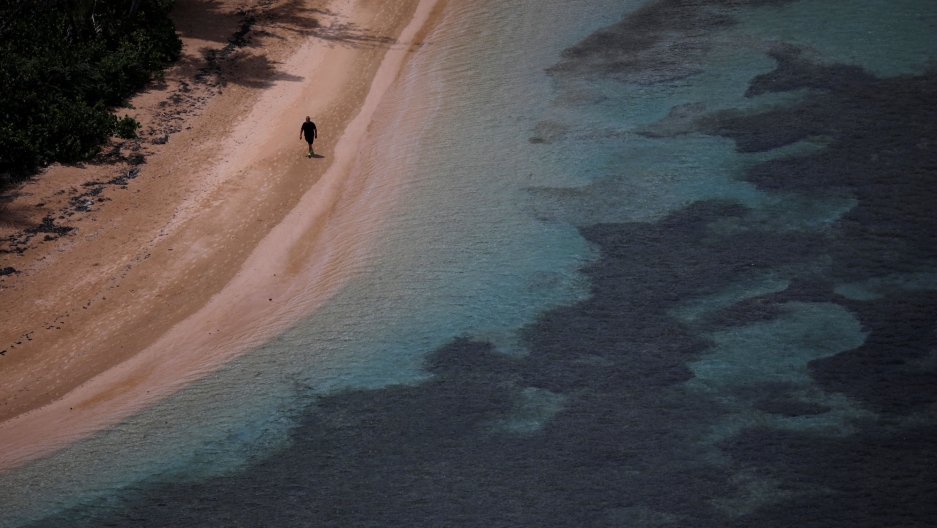 A man walks along an empty beach a year after Hurricane Maria devastated Puerto Rico near Ceiba, Puerto Rico, Sept. 18, 2018. A man walks along an empty beach light and dark blue waters near Ceiba, Puerto Rico, Sept. 18, 2018.