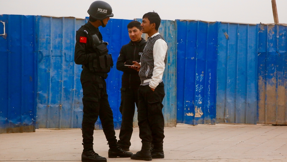 A Chinese police officer talks to men in a street in the city of Kashgar, in the Xinjiang Uighur Autonomous Region of China, on March 24, 2017. 