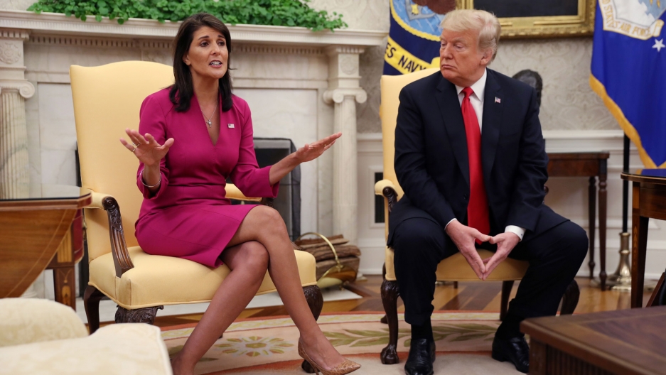Outgoing US Ambassador to the United Nations Nikki Haley talks with President Donald Trump in the Oval Office of the White House after the president accepted her resignation, Oct. 9, 2018. Outgoing US Ambassador to the United Nations Nikki Haley is shown in a pink dress sitting next to President Donald Trump wearing a dark blue suit and red tie.