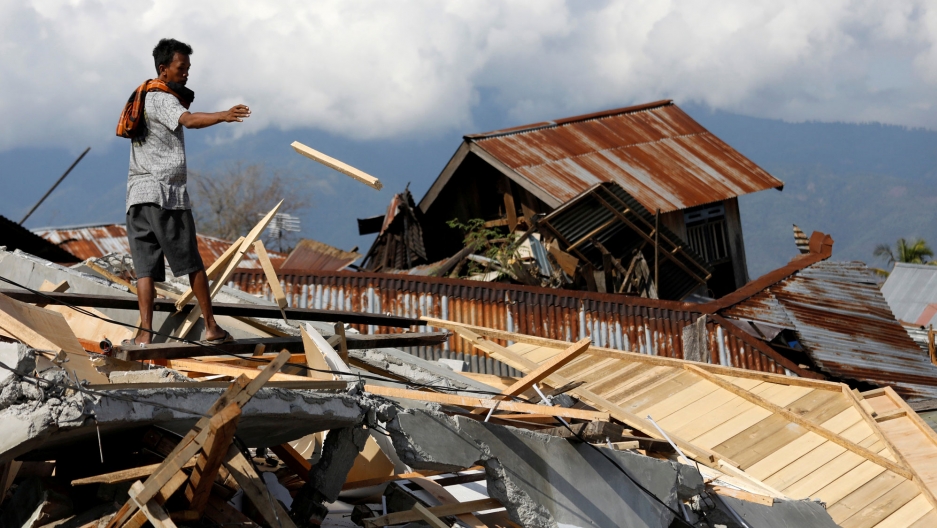 A man salvages wood from the ruins of a house in the Petobo neighborhood which was hit by an earthquake and liquefaction in Palu, Indonesia. A man is shown throwing a piece of wood from the ruins of a house in in Palu, Indonesia.