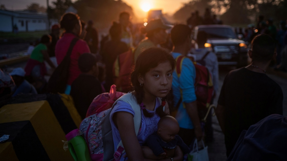 A girl traveling with a caravan of thousands of migrants from Central America en route to the United States holds her belongings while making her way to Mapastepec from Huixtla, Mexico at sunrise Oct. 24, 2018. A girl traveling with other migrants is shown holding a doll and wearing a back-pack en route to the United States.