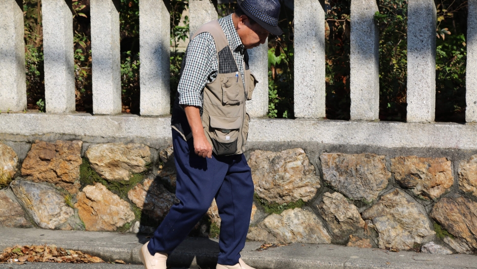 Iwao Hakamada walks in front of a fence