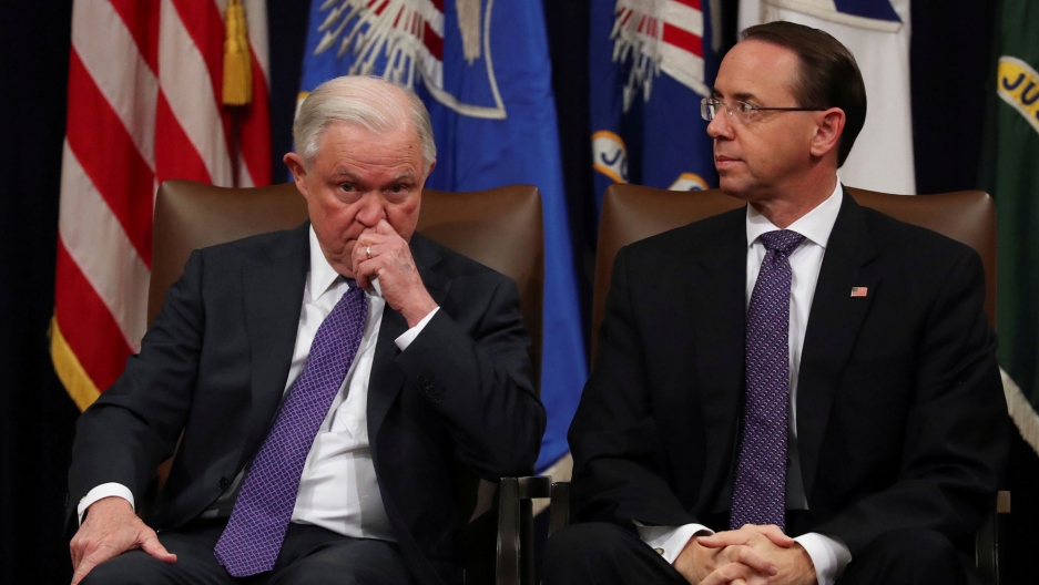 Then US Attorney General Jeff Sessions and Deputy Attorney General Rod Rosenstein at the Justice Department in Washington. US Attorney General Jeff Sessions is shown with his hand to his face sitting next to Deputy Attorney General Rod Rosenstein.