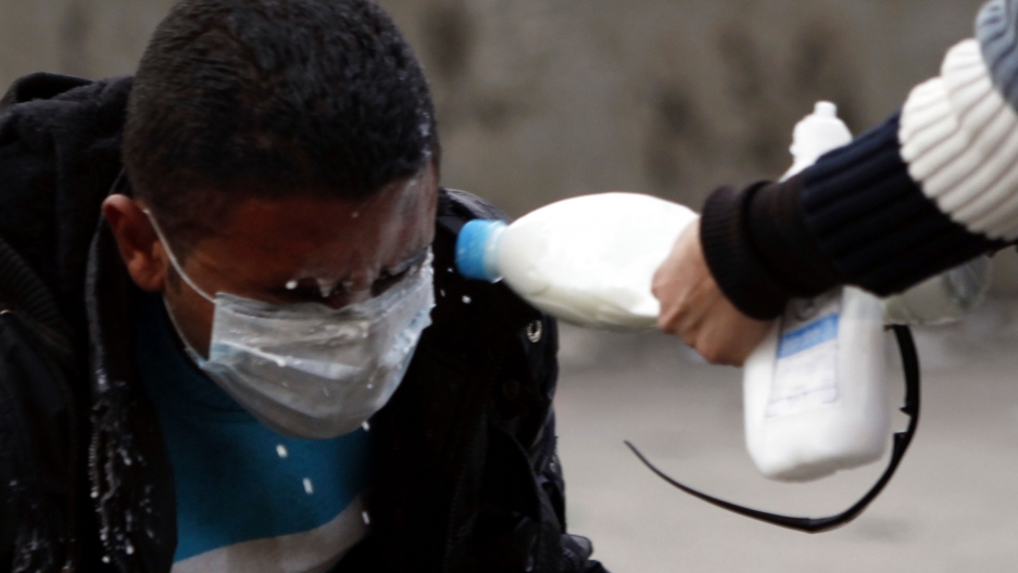 A man has milk splashed into his eyes to wash out tear gas.