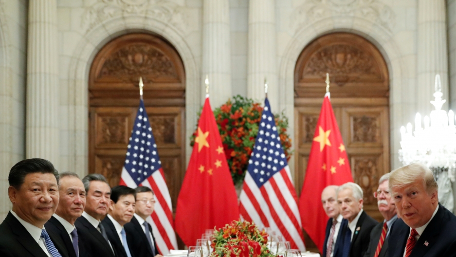 US President Donald Trump, Chinese President Xi Jinping and other leaders all sit around a table, looking at the camera