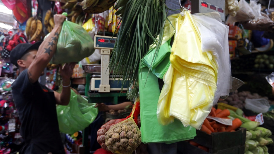 A vendor holds a green plastic bag at a market in Lima, Peru