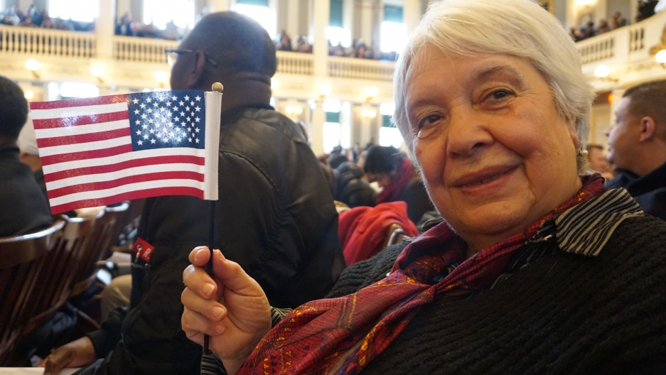a close up on Natalia Malkes waving a small flag during her citizenship ceremony