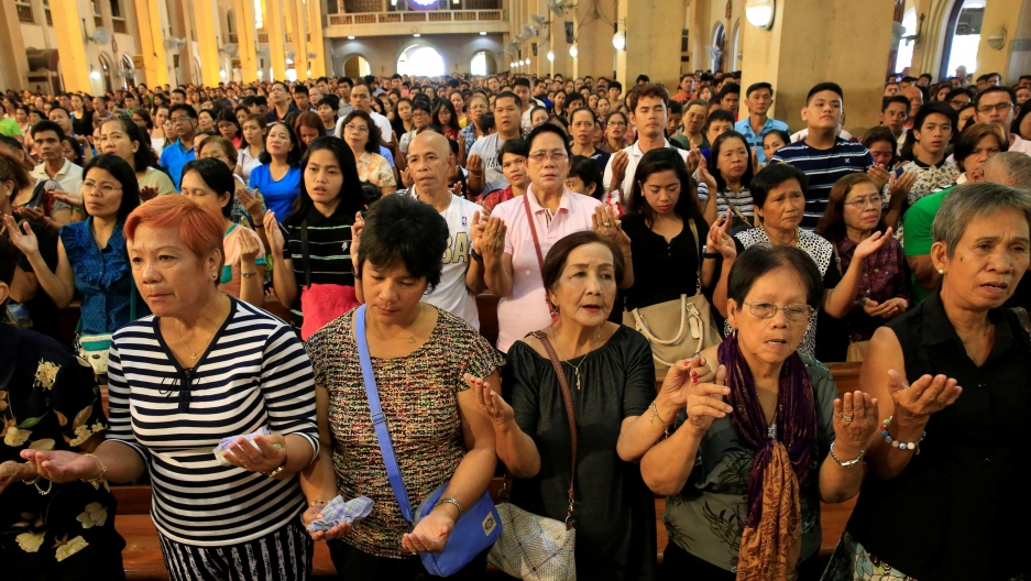 dozens of Filipino church goers praying
