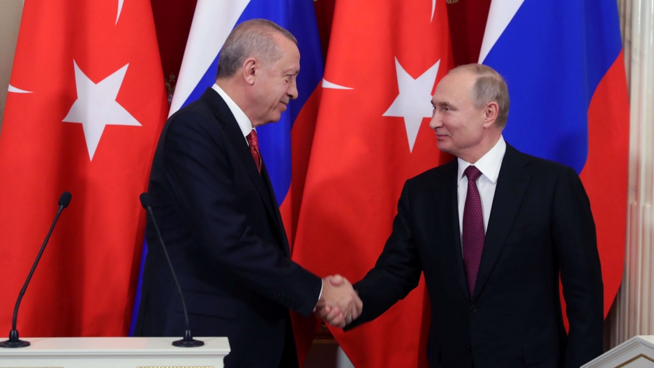 Russian President Vladimir Putin and his Turkish counterpart Tayyip Erdogan shake hands in front of their nations' flags