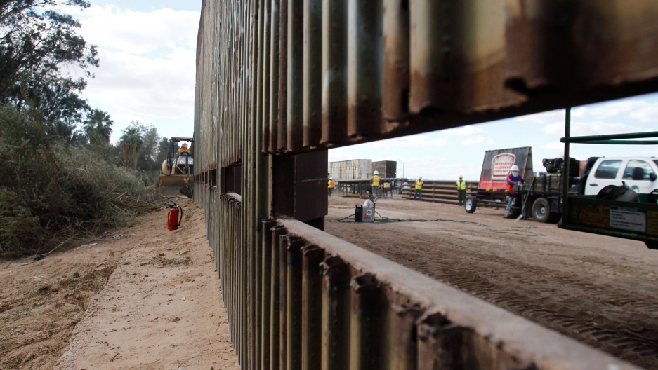 a portion of the US Mexico border. a whole in the wall allows you to see the other side