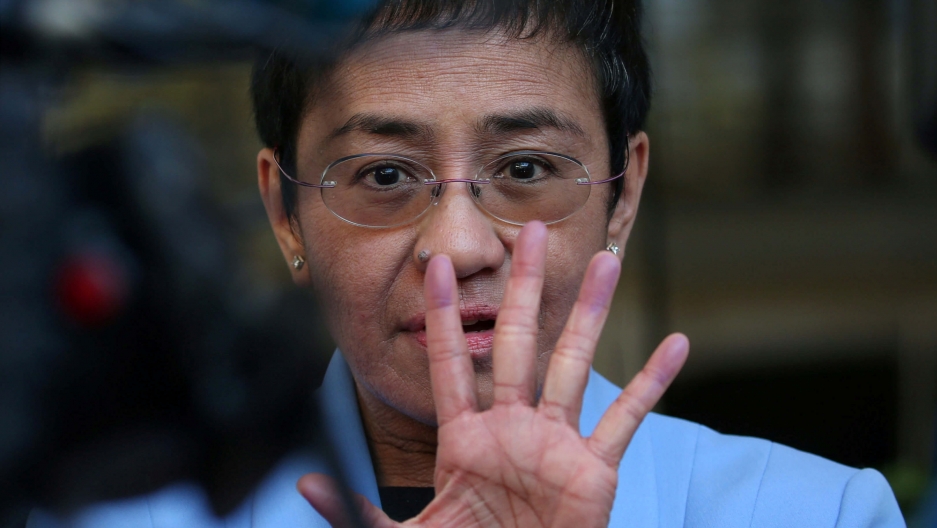 Maria Ressa, an executive of the online news platform Rappler, speaks to the media after posting bail for tax evasion charges. A closeup of Maria Ressa with her hand up in front of her face.