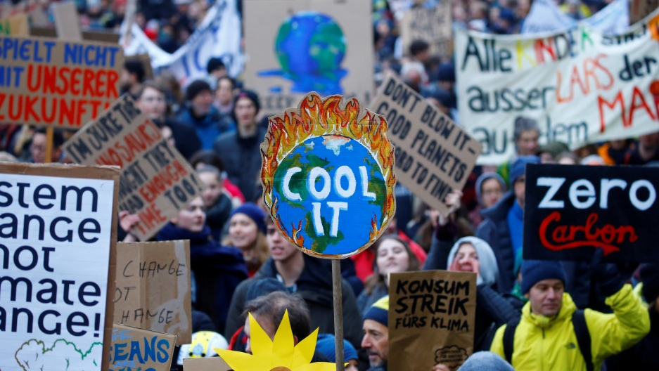 a large crowd of people marching, a sign that read "cool it" is the most prominent
