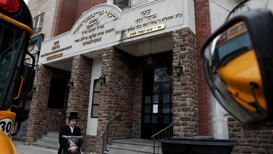 An Orthodox Jewish man walks by the Yeshiva Kehilath Yakov school in Brooklyn. An Orthodox Jewish man is shown walking past the brick facade of the Yeshiva Kehilath Yakov school in Brooklyn.