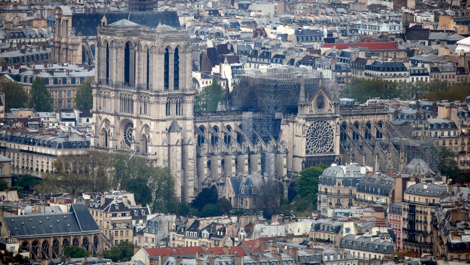 A view of the Notre-Dame Cathedral after a massive fire devastated large parts of the gothic structure in Paris, France, April 16, 2019. A wide photograph showing the city of Paris with the Notre-Dame Cathedral in the middle of the frame.