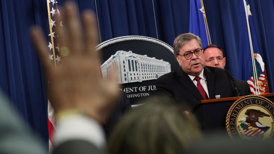 US Attorney General William Barr, flanked by Deputy Attorney General Rod Rosenstein, speaks at a news conference to discuss Special Counsel Robert Mueller's report on Russian interference in the 2016 US presidential election, April 18, 2019. US Attorney General William Barr is shown standing at a podium with the Department of Justice emblem on it, flanked by Deputy Attorney General Rod Rosenstein.