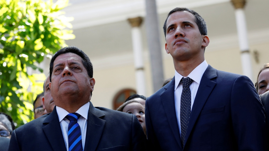 Venezuelan opposition leader Juan Guaidó (R) and lawmaker Edgar Zambrano of Democratic Action party (Accion Democratica), leave the congress after Guaido's swearing-in ceremony, in Caracas, Venezuela, January 5, 2019. Venezuelan opposition leader Juan Guaidó (R) and lawmaker Edgar Zambrano are shown on a sunny day both wearing a suit and tie.
