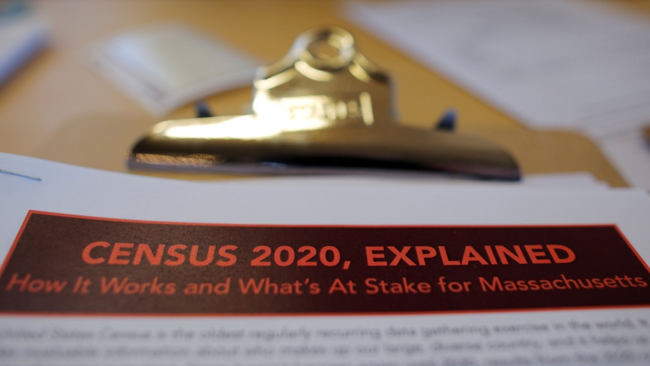 An census informational pamphlet is displayed at an event in Boston, Massachusetts. A paper is shown on a clipboard with a gold-colored clasp.