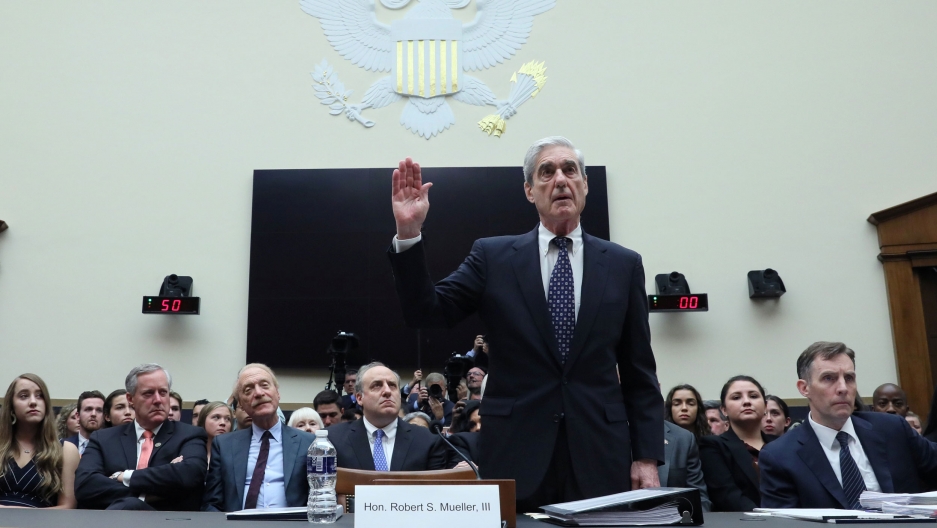 Former Special Counsel Robert Mueller testifies before a House Judiciary Committee hearing on Capitol Hill in Washington, July 24, 2019. Former Special Counsel Robert Mueller is shown with his right hand raised with a crowd of people seated behind him.