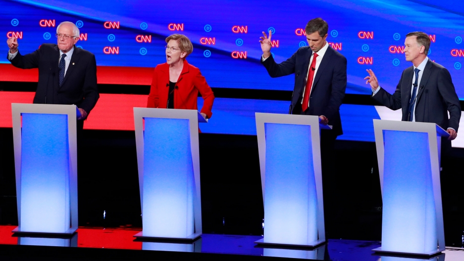 US Senators Bernie Sanders and Elizabeth Warren, former US Representative Beto O'Rourke and former Colorado Governor John Hickenlooper (L-R) debate during the second 2020 Democratic presidential debate, July 30, 2019. Three men and one woman are shown standing next to each other on a stage behind blue podiums.