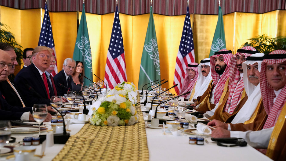 US President Donald Trump attends a working breakfast meeting with Saudi Arabia's Crown Prince Mohammed bin Salman during the G20 leaders summit in Osaka, Japan, June 29, 2019. A long table is shown from one end with President Trump's dark-suit-clad team sits across from Saudi Arabia's Crown Prince Mohammed bin Salman's team wearing traditional checkered head dresses.