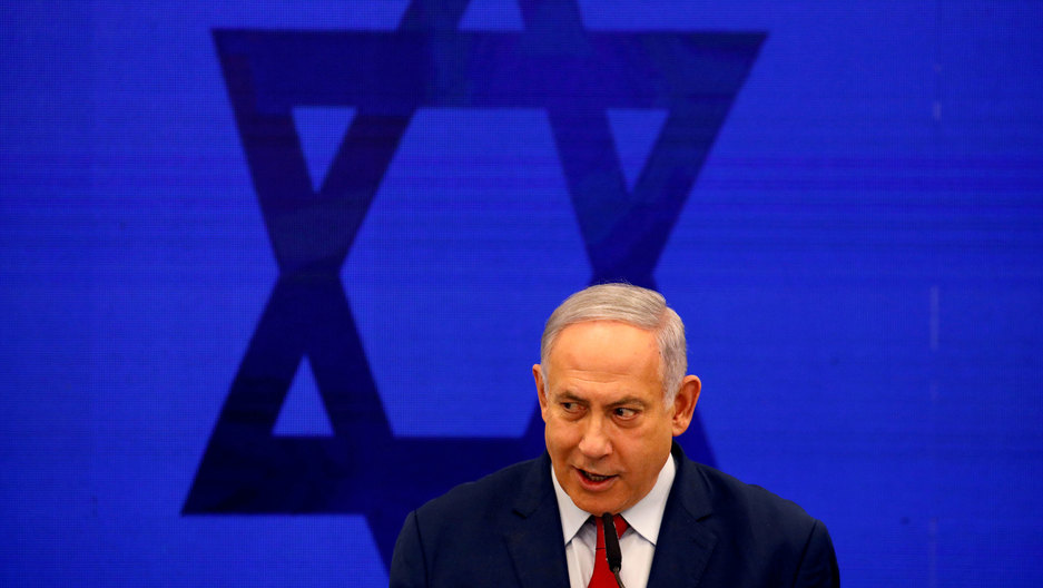 Israeli Prime Minister Benjamin Netanyahu delivers a statement in Ramat Gan, near Tel Aviv, Israel. Israeli Prime Minister Benjamin Netanyahu is shown wearing a dark suit and red tie with the Star of David behind him.