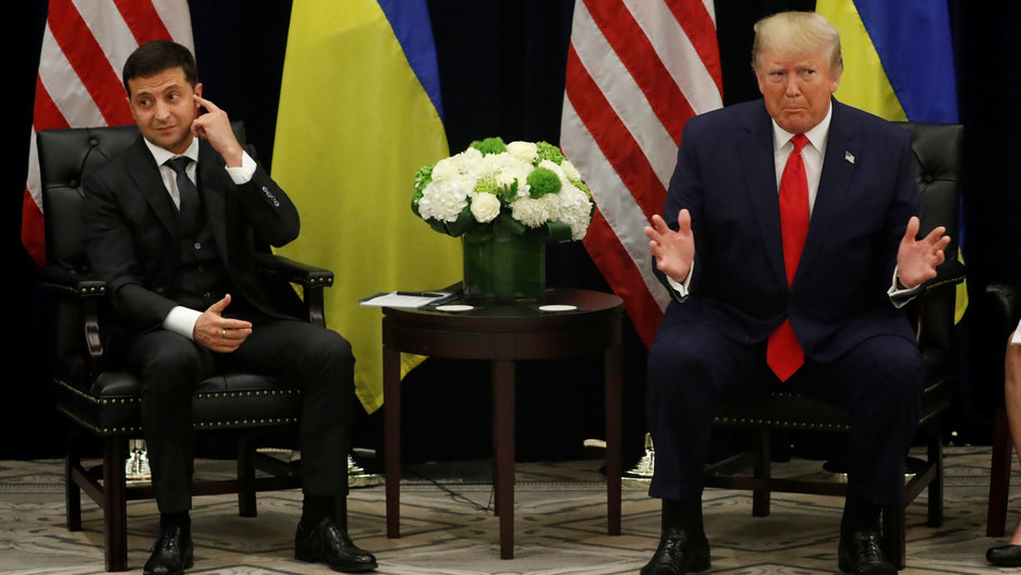 Ukraine's President Volodymyr Zelenskiy listens to US President Donald Trump speak to reporters during a meeting on the sidelines of the United Nations General Assembly in New York City, Sept. 25, 2019. Ukraine's President Volodymyr Zelenskiy is shown seated next to US President Donald Trump with their respective flags placed behind them.