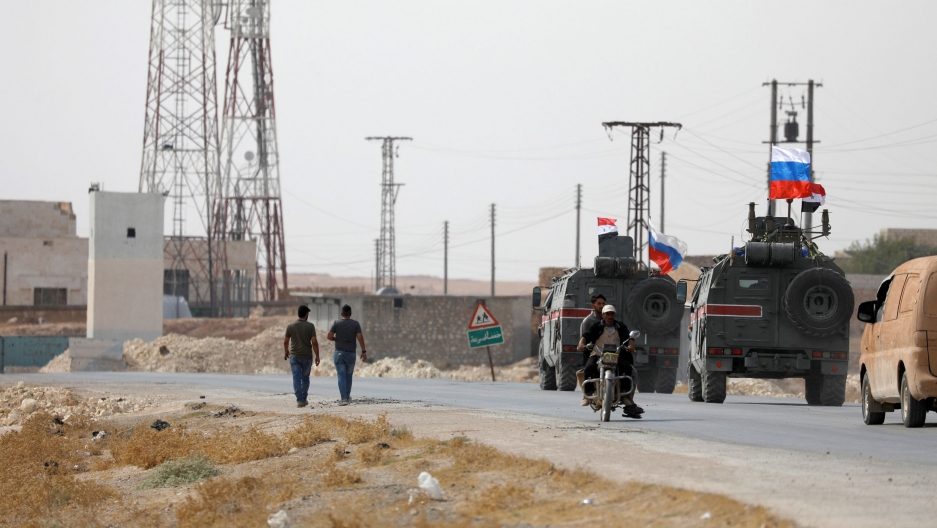 Russian and Syrian flags flutter on military vehicles near Manbij, Syria, Oct. 15, 2019. Two military trucks are show driving with Russian and Syrian flags flying on top.