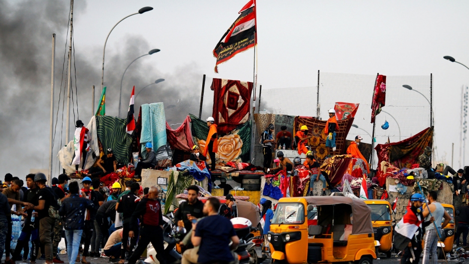 Iraqi demonstrators block Al-Sanak Bridge during the ongoing anti-government protests in Baghdad, Iraq. A large group of protesters are shown blocking a bridge in Baghdad.